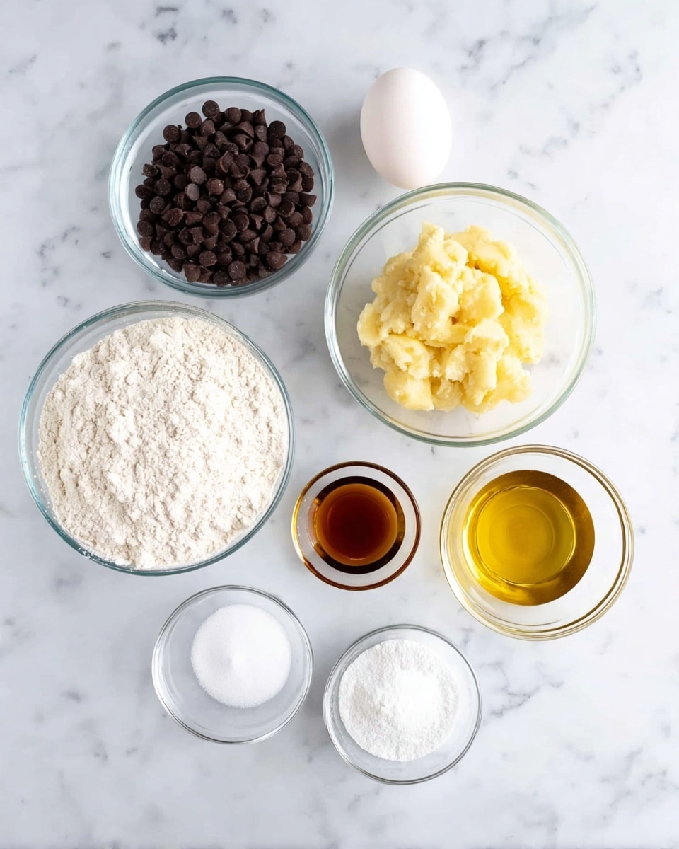 The image shows eight clear glass bowls of different sizes placed on a white marbled surface. From the top left moving clockwise, the first bowl is filled with dark brown chocolate chips, the next one is empty and small, the next bowl contains mashed yellow bananas with a soft texture. Below it, a small bowl holds a dark amber liquid, likely vanilla extract. Next is a larger bowl filled with a light golden oil. Near the center bottom, a very small bowl contains a white powder, probably baking soda or salt. To the left of it is a large bowl filled with white granulated sugar. Above that is a white egg placed directly on the surface near a large bowl filled with white flour. The bowls and egg are neatly arranged in a circular layout, with contrasting textures and colors visible through the clear glass. Photo taken with an iphone --ar 4:5 --v 7