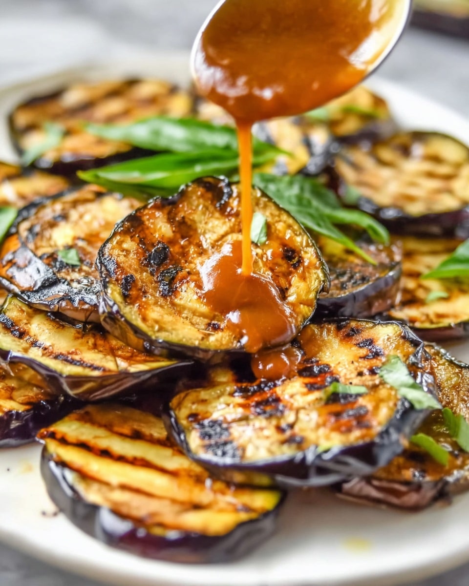 The image shows a close-up of grilled eggplant slices with deep brown grill marks, arranged overlapping on a white plate. The eggplant slices are mostly golden brown with darker charred lines and patches, showing their soft, cooked texture. Part of a woman's hand is visible holding a spoon that is pouring a shiny, smooth brown sauce over the eggplants. In the background, fresh green basil leaves add a splash of color and freshness. The plate rests on a white marbled surface. photo taken with an iphone --ar 4:5 --v 7