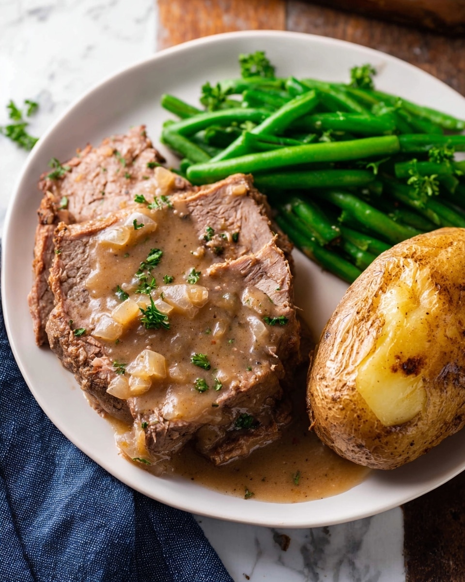 A white plate holds a meal with three main parts: on the left, slices of tender brown meat covered in a light brown gravy with small bits of onion and green parsley sprinkled on top; in the upper middle, bright green pieces of steamed beans piled neatly; on the right, a whole baked potato with a golden, slightly crispy skin sitting next to the meat. The plate rests on a white marbled surface with a dark blue cloth partially visible at the bottom edge. photo taken with an iphone --ar 4:5 --v 7