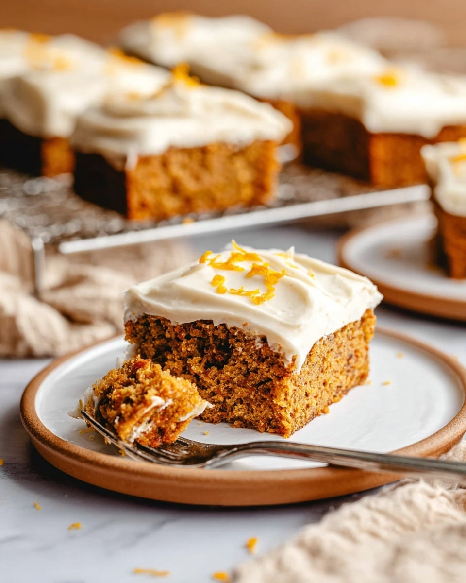 A square piece of moist carrot cake with a thick layer of creamy white frosting on top sits on a white plate with a tan rim, with some orange zest sprinkled on the frosting. The cake is light brown and textured, showing bits of carrot and a spongy crumb. A fork with a small bite of cake is resting beside the piece on the plate. In the background, more square pieces of the same cake with white frosting are on a white cooling rack on a white marbled surface, with a blurred beige cloth nearby. photo taken with an iphone --ar 4:5 --v 7