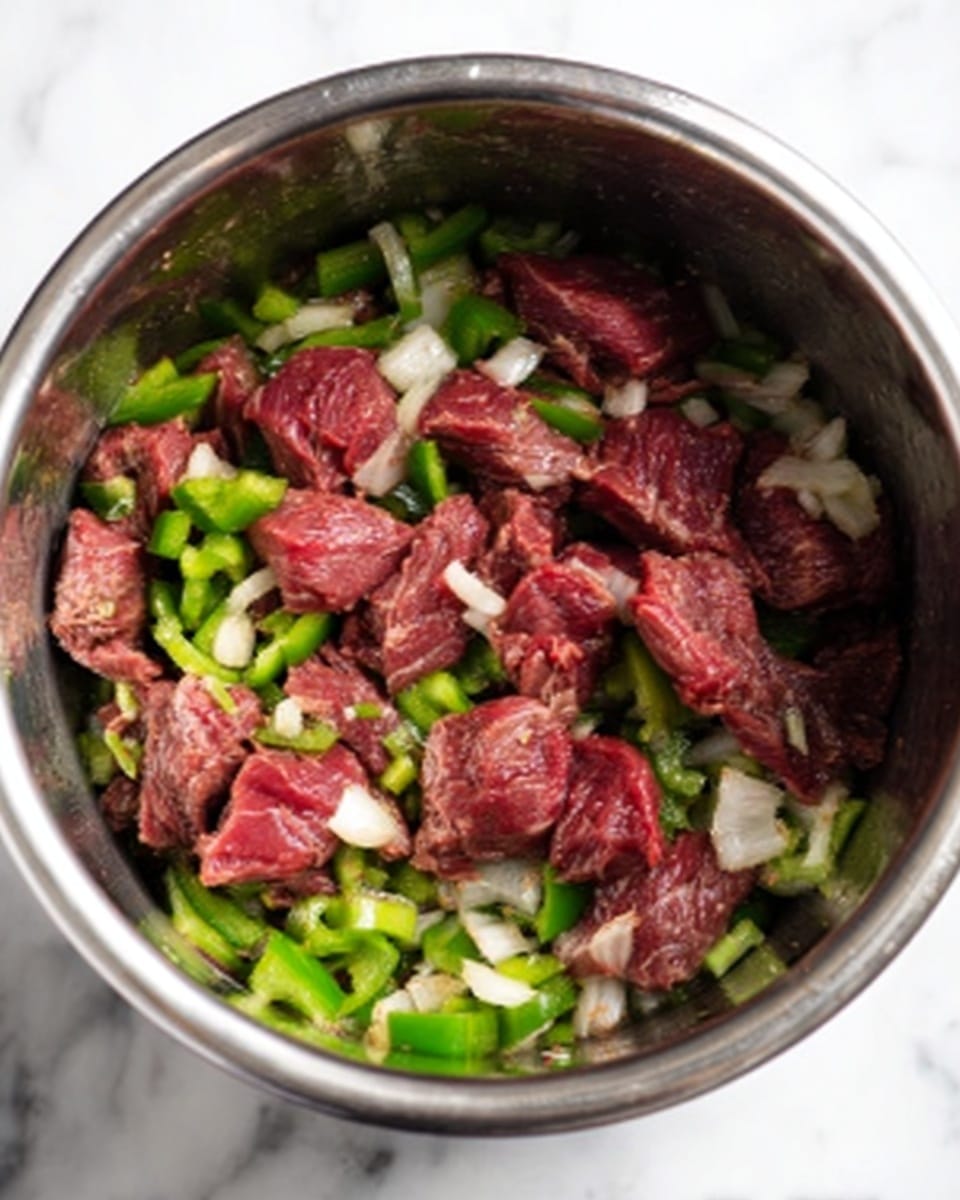 The image shows a shiny stainless steel pot on a white marbled surface, filled with raw thin slices of red beef layered on top of a bed of chopped green bell peppers and white onions. The beef pieces appear fresh and rich in color, scattered unevenly across the vegetables, which add a mix of bright green and off-white colors below. The pot's metallic surface reflects some light, creating a clean and simple cooking scene. Photo taken with an iphone --ar 4:5 --v 7
