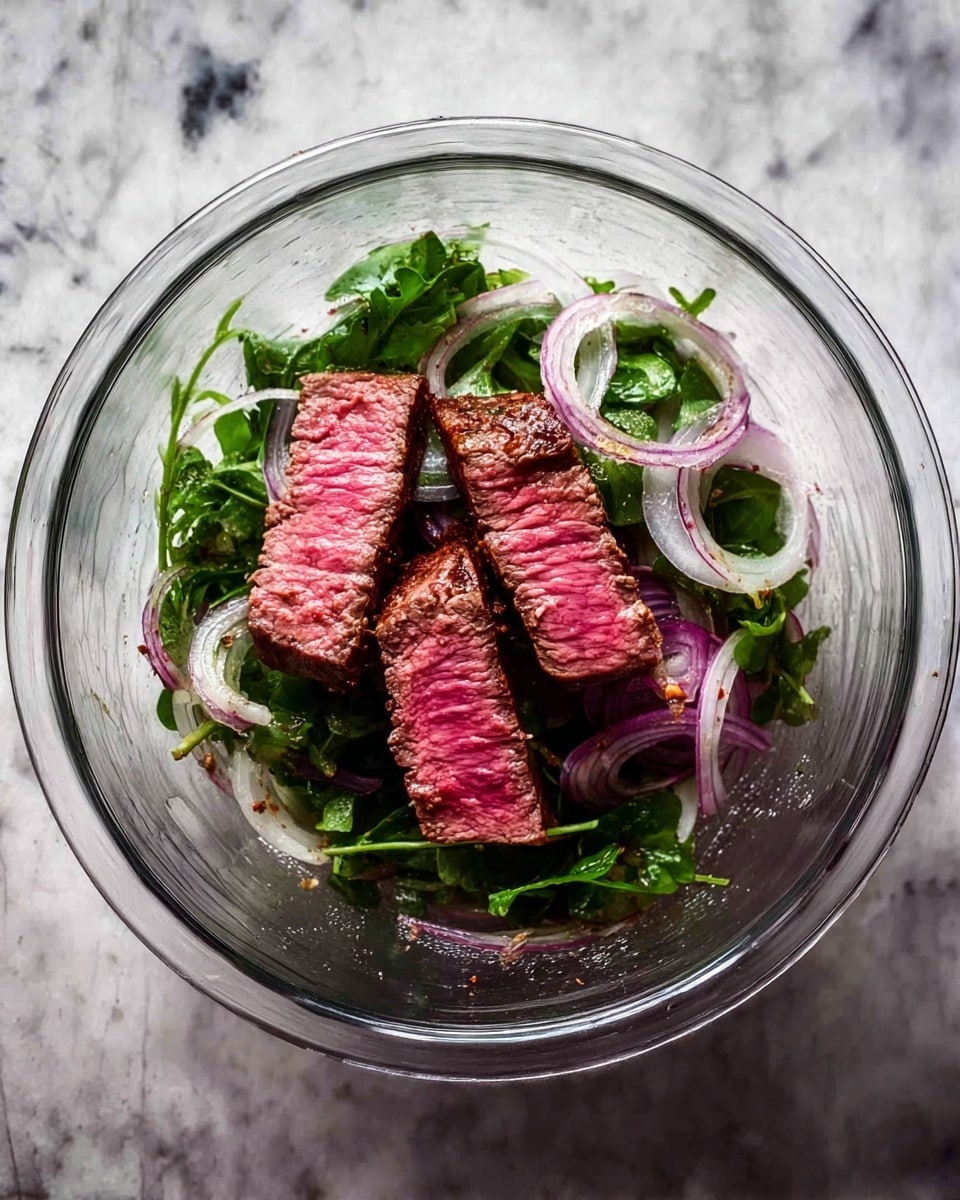 A clear glass bowl sits on a white marbled surface, holding three thick slices of medium-rare steak with a pink center and browned edges placed on top of thinly sliced purple onions and a bed of fresh green leafy herbs. The steak pieces stand out with their juicy texture, layered over the translucent, round onion slices and the vibrant green herbs below, creating a fresh and colorful contrast. Photo taken with an iphone --ar 4:5 --v 7