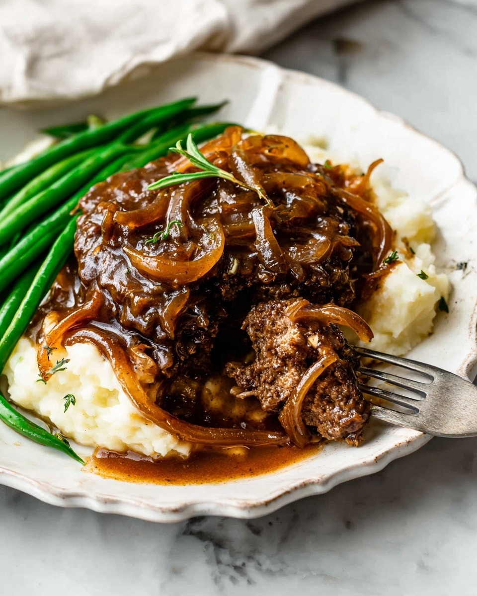 On a white scalloped plate over a white marbled surface, there is a three-layered dish. The bottom layer is creamy white mashed potatoes, smooth in texture and spread evenly. On top of that lies a thick, dark brown meat patty covered in glossy brown gravy with caramelized onions, giving a shiny and textured look with some herbs mixed in. Bright green steamed green beans rest on one side, adding a fresh, crisp contrast. A silver fork is placed on the right side of the plate, holding a piece of the meat patty. photo taken with an iphone --ar 4:5 --v 7
