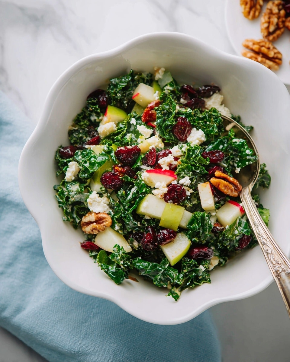 A white scalloped bowl filled with a kale salad showing three main layers: dark green kale leaves as the base, mixed with light green and white cubed pears and thinly sliced radishes. On top, there are dark red dried cranberries and brown walnut halves scattered throughout, along with small white crumbles of cheese. A silver spoon is placed in the bowl, partly buried in the salad. The bowl rests on a white marbled surface with a light blue cloth nearby. photo taken with an iphone --ar 4:5 --v 7