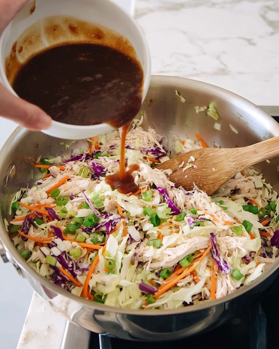 A woman's hand is pouring a rich dark brown sauce from a white bowl into a large stainless steel pan filled with a mix of shredded white meat, thin slices of white cabbage, bright orange carrot strips, pieces of purple cabbage, and chopped green onions. The mixture is spread evenly in the pan with a wooden spoon resting on one side. The pan sits on a white marbled stove surface, showing a clean and bright kitchen setting. Photo taken with an iphone --ar 4:5 --v 7