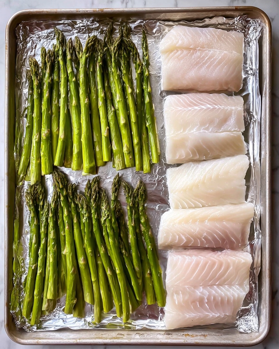 A sheet pan covered with shiny silver foil holds two main items: on the left side, there is one layer of fresh green asparagus spears, all lined up neatly with their tips pointing left, showing a bright and smooth texture. On the right side, there are four pieces of raw white fish fillets, arranged in two rows with two fillets each; the fish has smooth, slightly translucent flesh with some faint lines and a softer white color. The entire setup is on a white marbled surface. photo taken with an iphone --ar 4:5 --v 7