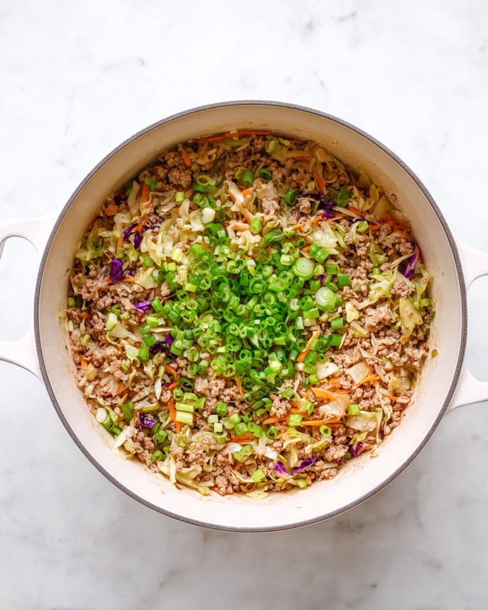 A white pot filled with a mix of finely chopped cooked ingredients showing about five layers: a base layer of light brown cooked ground meat, mixed with finely shredded pale cabbage and thin orange carrot strips, dotted with small bits of purple cabbage. On top, a generous sprinkle of bright green chopped spring onions covers the surface, adding fresh color. The textures show a combination of soft cooked vegetables and tender meat, with the pieces evenly spread. The pot is placed on a white marbled texture surface. Photo taken with an iphone --ar 4:5 --v 7