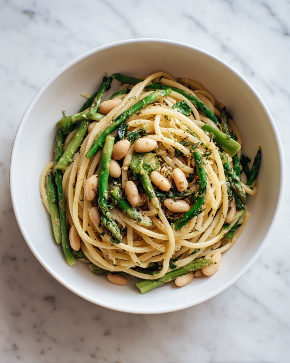 A close-up of a white bowl filled with a noodle dish showing about three main layers: the base layer of light-colored thin noodles with a slightly rough texture, mixed with small white beans; the middle layer contains pieces of green asparagus and herbs giving a fresh, green touch; the top layer is sprinkled with bright green parsley leaves and bits of herbs scattered evenly, adding a fresh look. The bowl is set on a white marbled surface with a soft natural light giving the noodles a warm tone photo taken with an iphone --ar 4:5 --v 7
