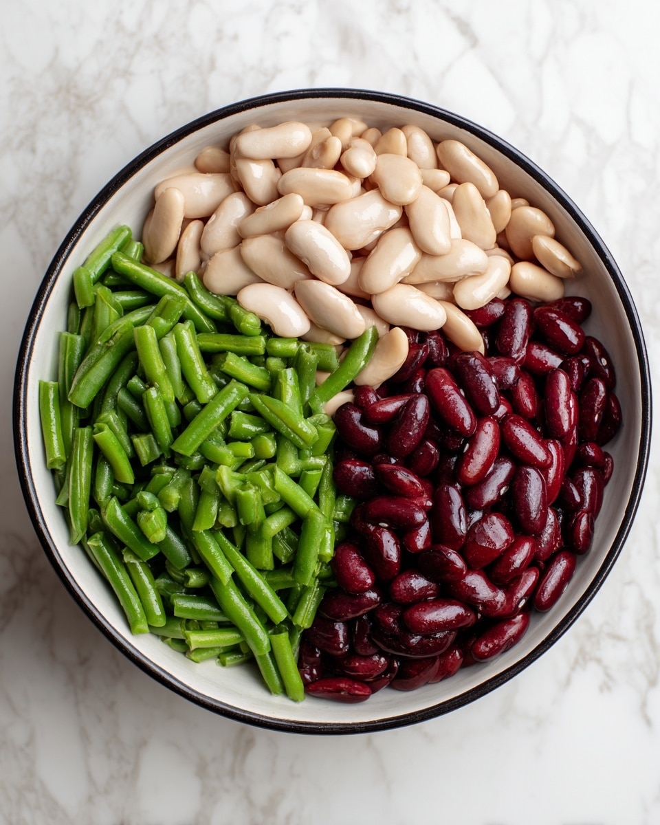 A white bowl with a black rim sits on a white marbled surface, containing three separate piles of beans. One pile shows bright green chopped green beans with a smooth texture on the left side of the bowl. To the top right, light beige cannellini beans with a soft, smooth surface are placed closely together. The bottom right section has dark red kidney beans that are shiny and smooth, creating a strong color contrast with the other two piles. The beans are neatly arranged without mixing, showing clear separation between each color and texture. Photo taken with an iphone --ar 4:5 --v 7