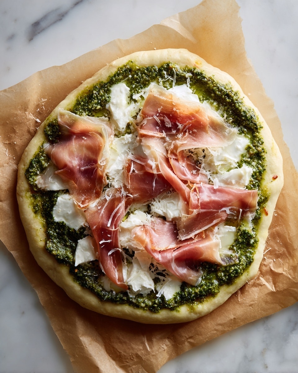 A round, thick layer of dough spreads out with a slightly uneven edge as the base, topped with a spread of bright green pesto sauce forming a rough circle near the center. On top of the pesto, there are white, soft chunks of cheese scattered unevenly, followed by several thin, translucent slices of light pink cured meat laid loosely over the cheese, showing some areas where the dough and pesto peek through. The entire preparation rests on a light brown parchment paper with slight wrinkles, placed on a white marbled surface. photo taken with an iphone --ar 4:5 --v 7