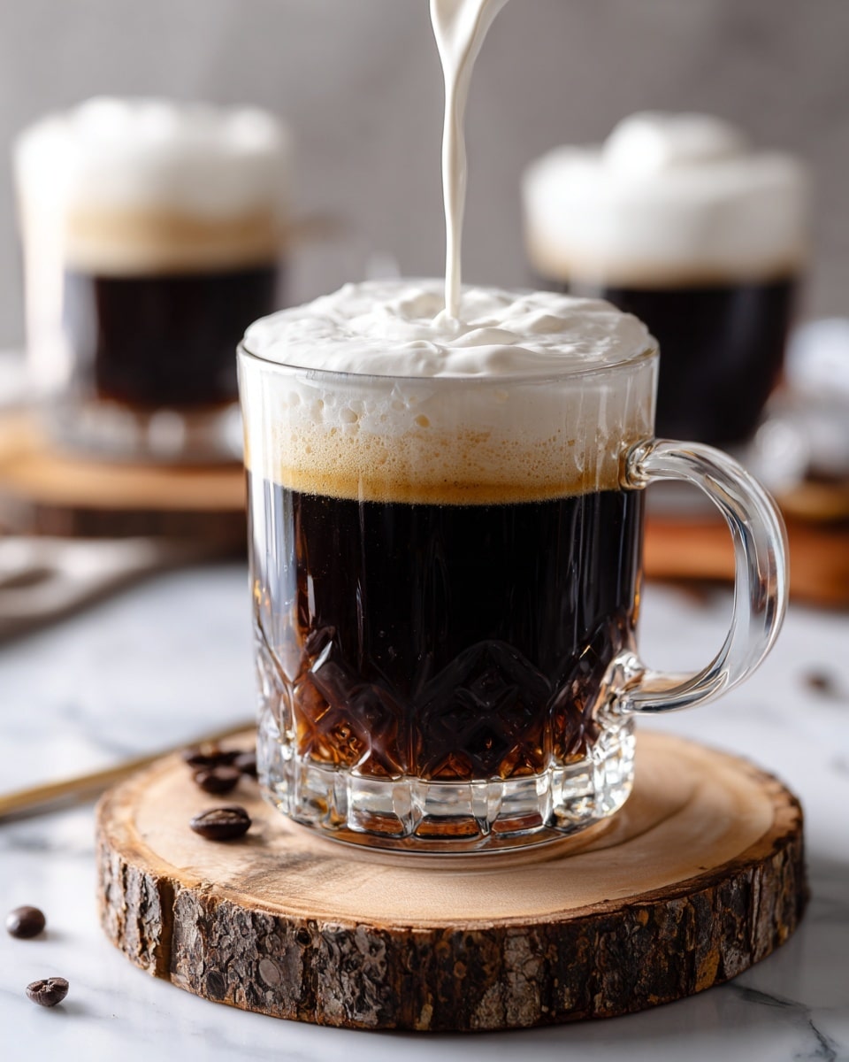 A clear glass mug filled with dark black coffee sits on a round wooden coaster with bark edges, placed on a white marbled surface. Above the coffee, a thick layer of white cream is being poured down in a smooth, soft stream, starting to form a fluffy top layer on the coffee. In the blurred background, two more glass mugs filled with black coffee are visible, one of them topped with white cream. A few dark coffee beans rest on the white marbled surface near the wooden coaster. The lighting is bright and natural, highlighting the contrast between the dark coffee and the white cream. photo taken with an iphone --ar 4:5 --v 7