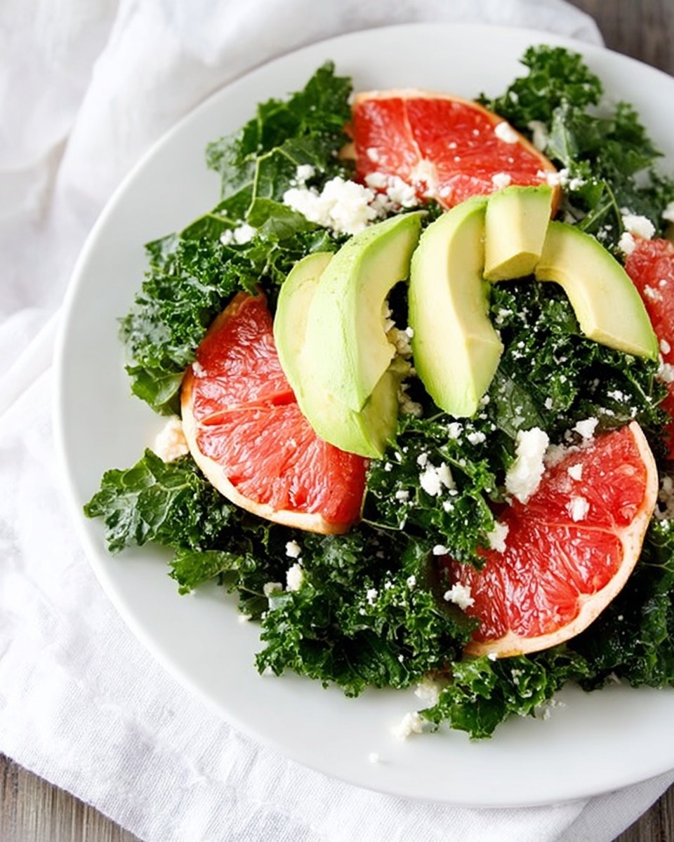 A white plate filled with deep green curly kale leaves as the base layer, topped with bright red citrus slices with a soft, juicy texture, and light pink grapefruit segments. On top of the fruits, there are smooth, pale green avocado slices arranged evenly. Small white crumbles of cheese are scattered over the entire salad, adding contrast to the colors and textures. The plate sits on a white marbled surface with a white cloth partially visible under the plate. photo taken with an iphone --ar 4:5 --v 7