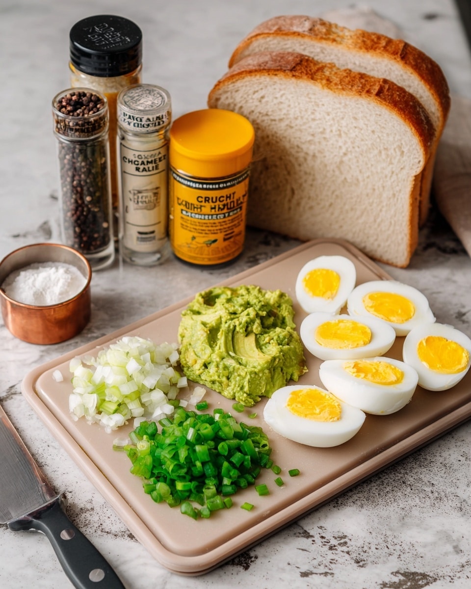 A beige cutting board is placed on a white marbled textured surface. On the cutting board, there are three main layers: at the bottom left, a pile of chopped green onion pieces, with a smooth, juicy texture; to the right of the green onions, there is a mash of bright green avocado spread unevenly, showing some chunks; on the far right side, there are two rows of cleanly sliced boiled eggs, with white outer layers and bright yellow yolks in the center. Behind the cutting board, there are two large slices of light brown crusty bread leaning on each other. Behind the bread, from left to right, there are three containers: a clear bottle filled with black peppercorns, a clear bottle with white salt, a yellow-lidded colorful container labeled