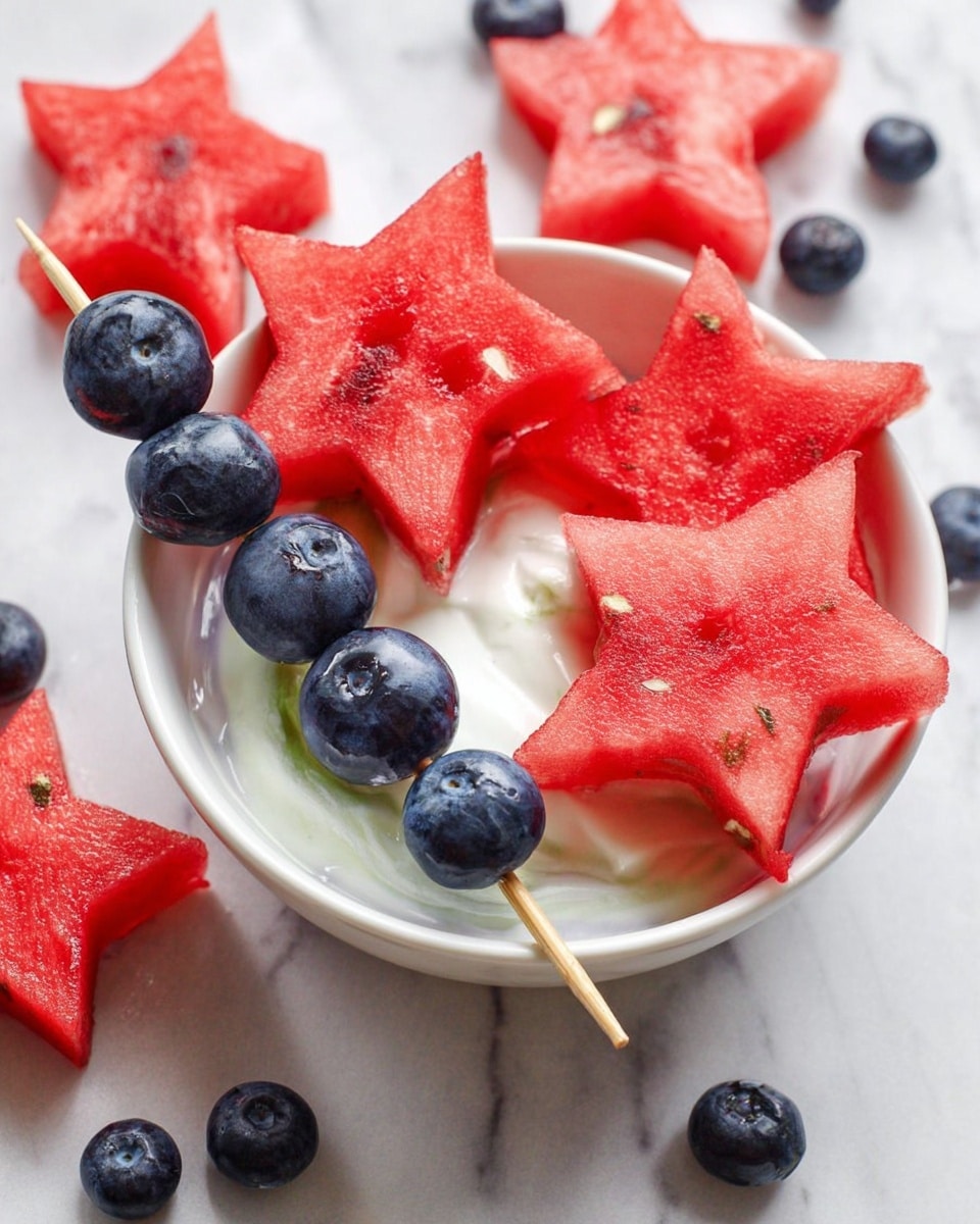 The image shows red watermelon star shapes and dark blue blueberries on wooden skewers. One skewer with five blueberries and a watermelon star is resting inside a round white bowl filled with white creamy yogurt or sauce. Surrounding the bowl are more watermelon stars and skewers with blueberries on a white marbled surface. The colors stand out with bright red watermelon, deep blue blueberries, and the smooth white cream. Photo taken with an iphone --ar 4:5 --v 7