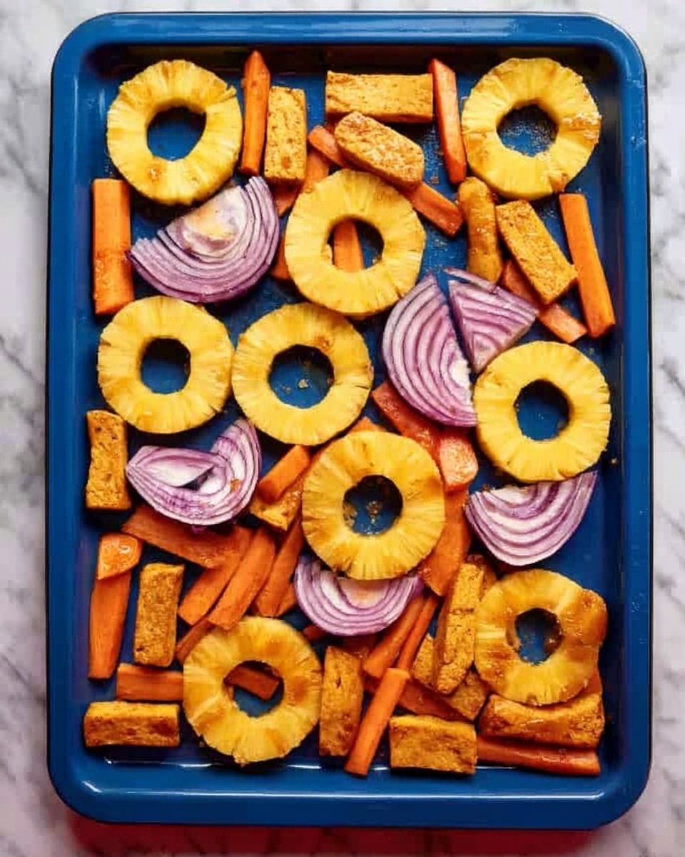 The image shows a blue baking tray filled with evenly spaced rings of yellow pineapple, pinkish semi-circular slices of onion, long orange carrot sticks, and brownish cubes and sticks of tofu. The pineapple rings have a smooth texture with a hole in the middle and are placed flat on the tray in a grid-like pattern. The onion pieces are layered with visible purple and white rings and are placed around the pineapple rings. The orange carrot sticks are long and thin with a rough texture, scattered between the pineapple and onion pieces. The tofu is in two shapes: small cubes and longer rectangular sticks, both having a rough, slightly crispy look. The tray rests on a white marbled surface. photo taken with an iphone --ar 4:5 --v 7