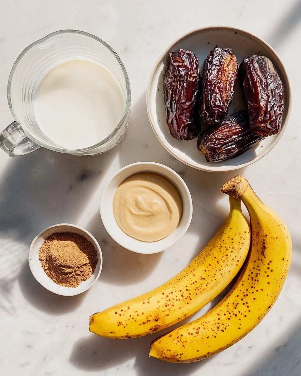 The image shows six ingredients placed on a white marbled surface. On the left, there is a clear glass jug filled with white milk. Above it, there is a white bowl holding four dark brown dried dates with wrinkled textures. Next to the dates, on the right, is a small white bowl filled with light tan creamy tahini. Below the tahini, there is a tiny white bowl with a heap of brown cinnamon powder. On the far right are two ripe yellow bananas with many brown spots on their skins. The scene is lit by natural light creating soft shadows around the items photo taken with an iphone --ar 4:5 --v 7