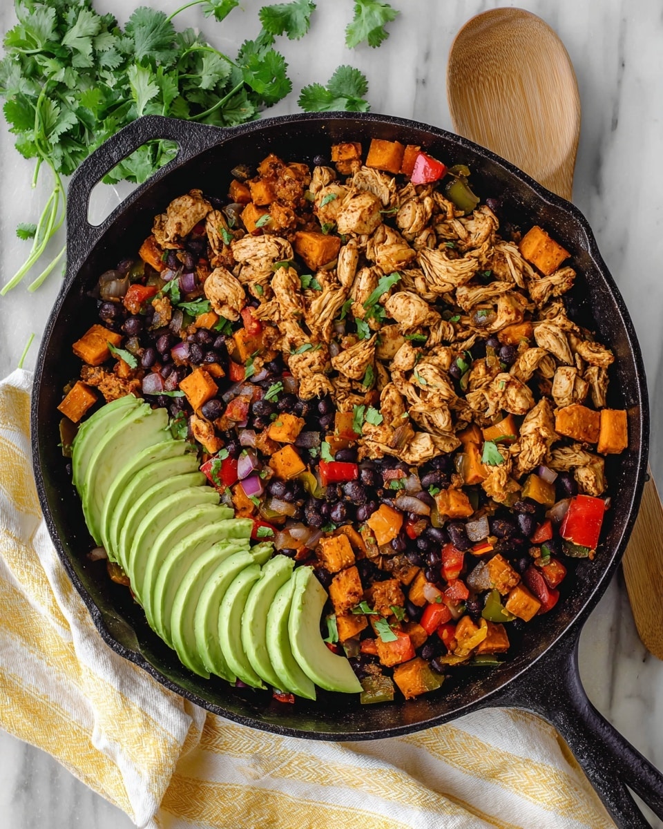 A black cast iron pan sits on a white marbled surface with a yellow and white striped cloth beside it. Inside the pan, there are several visible layers and colors: shredded cooked chicken pieces in light brown, small cubes of orange sweet potatoes, black beans, diced red and green bell peppers, and bits of cooked onions with a purplish tint. Fresh green cilantro leaves are scattered on top, adding a pop of color. On one side of the pan, there are thin slices of creamy green avocado arranged in a fan shape. A wooden spoon is partially visible next to the pan. photo taken with an iphone --ar 4:5 --v 7
