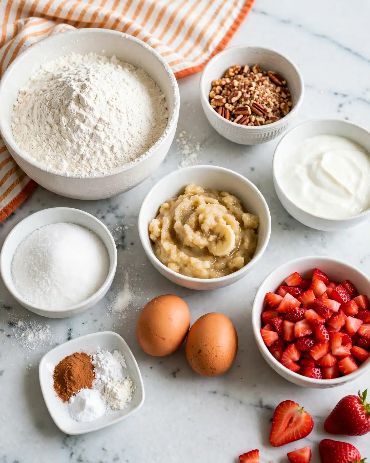Strawberry Banana Bread Recipe 4 The image shows an arrangement of baking ingredients placed on a white marbled surface. There is a large white bowl filled with white flour on the left, next to a smaller white bowl of white sugar below it. To the right, a small white bowl holds chopped nuts, with another containing white cream or yogurt near it. In the center, a white bowl has mashed bananas, while below it, two brown eggs rest directly on the surface. A small white dish contains a mix of spices, including cinnamon powder and white powders. In the bottom right, a white bowl is filled with chopped red strawberries. All the bowls are white with different shapes and textures, neatly spaced. Photo taken with an iphone --ar 4:5 --v 7