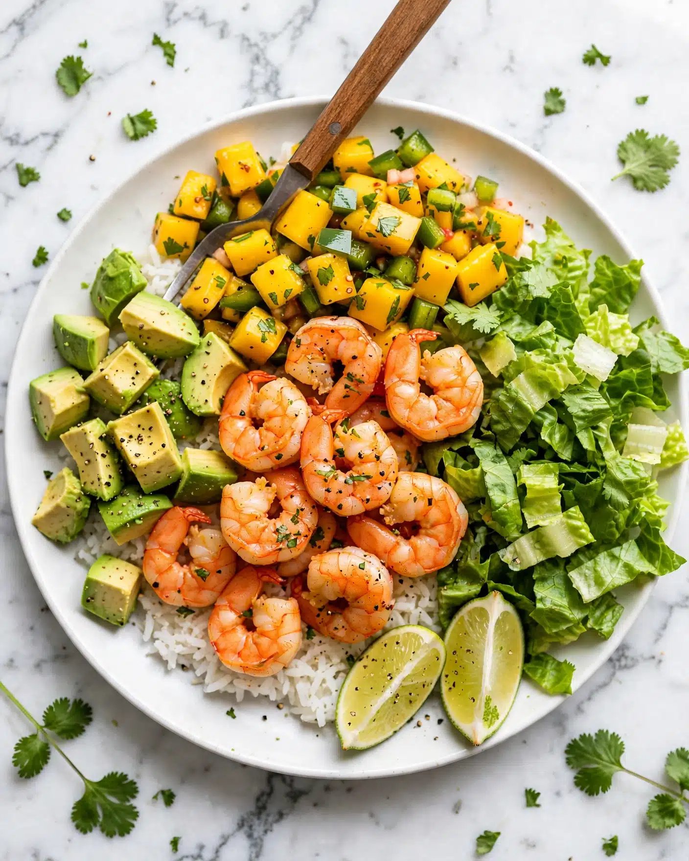 Quick & Easy Shrimp Rice Bowls with Mango Salsa Recipe 5 A white round plate holds a colorful rice bowl with several layers: the base is white rice, topped with bright orange shrimp seasoned with black pepper, and chunks of yellow mango mixed with green herbs and small diced green vegetables. To one side, there are chopped pieces of green avocado, sprinkled with black pepper, and fresh green leafy lettuce on the other side. Two lime wedges sit at the edge of the plate. A wooden-handled fork is placed inside the bowl. The background is white marbled texture with scattered green herbs nearby. Photo taken with an iphone --ar 4:5 --v 7