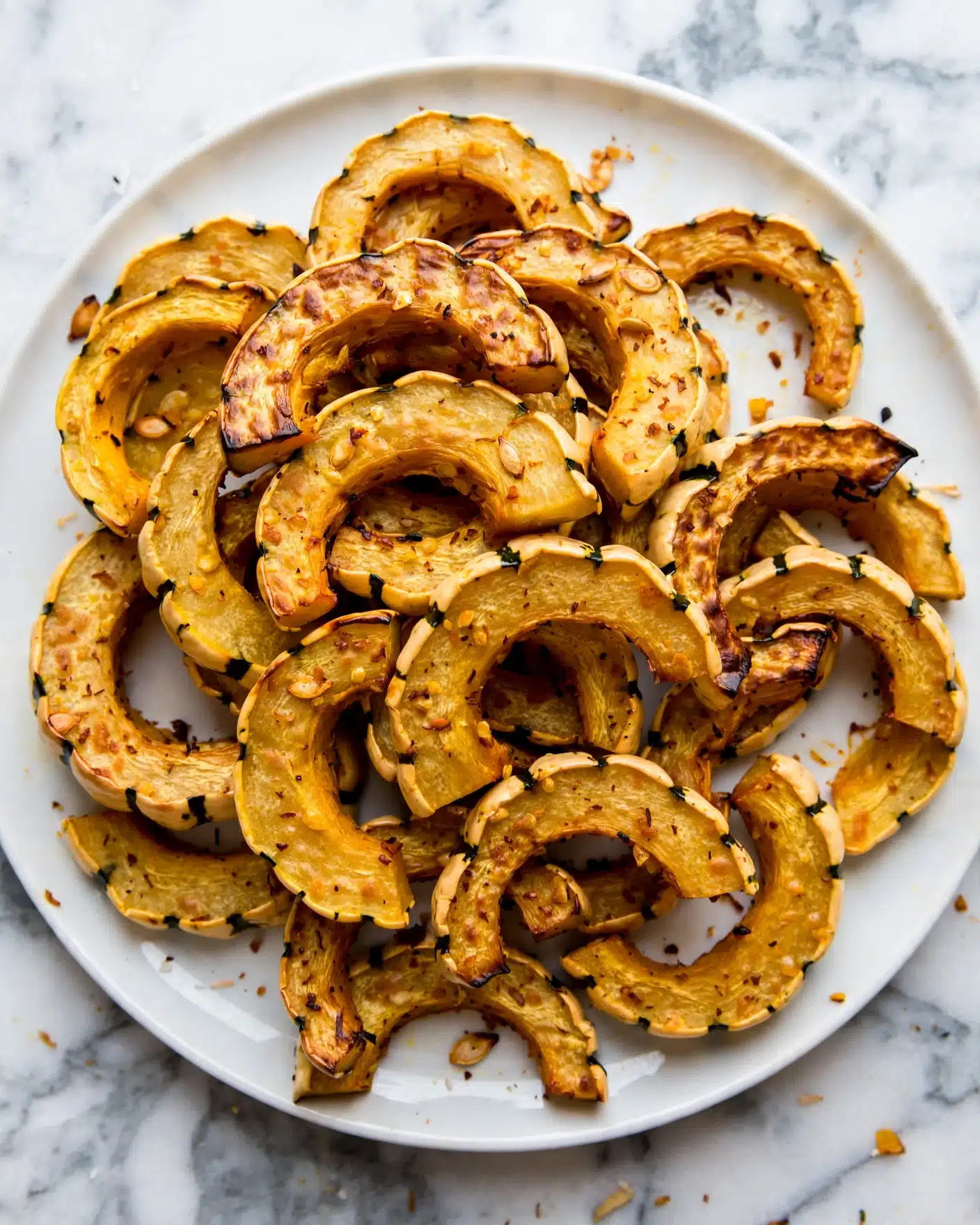 Many curved slices of roasted orange squash with dark green stripes, showing a soft, slightly browned texture on the inside, are stacked in a heap on a large white plate. The background is a white marbled surface. photo taken with an iphone --ar 4:5 --v 7
