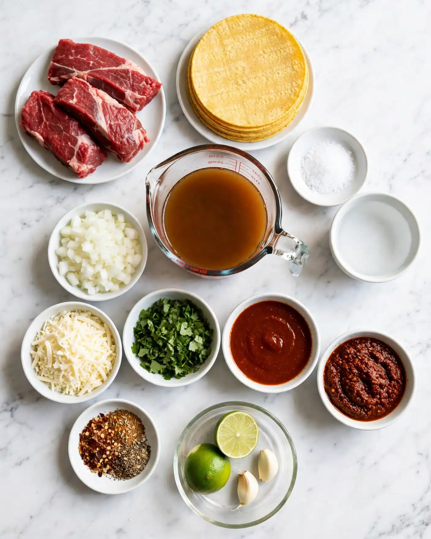 Slow Cooker Birria Tacos Recipe 4 A flat lay shows several cooking ingredients on a white marbled surface. In the top left, three pieces of raw red meat with white fat sit on a white plate. To the right, a stack of yellow corn tortillas is on a white plate. Nearby are small white dishes holding salt and water. Below, a clear glass measuring cup contains brown broth. Surrounding this are bowls with chopped white onion, shredded white cheese, bright green chopped cilantro, a deep red smooth sauce, and a dark reddish-brown chili mixture. There is also a small dish of mixed spices, two lime halves, and two peeled garlic cloves on a clear dish. photo taken with an iphone --ar 4:5 --v 7